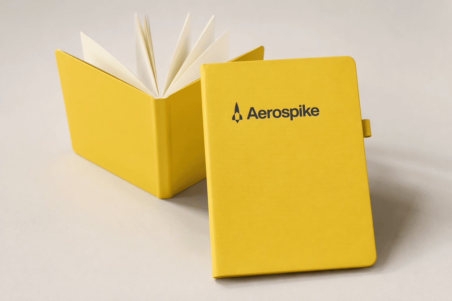 Aerospike — Branded A5 notebooks in Aerospike yellow, produced alongside 19-inch sleeved umbrellas as a matched set.